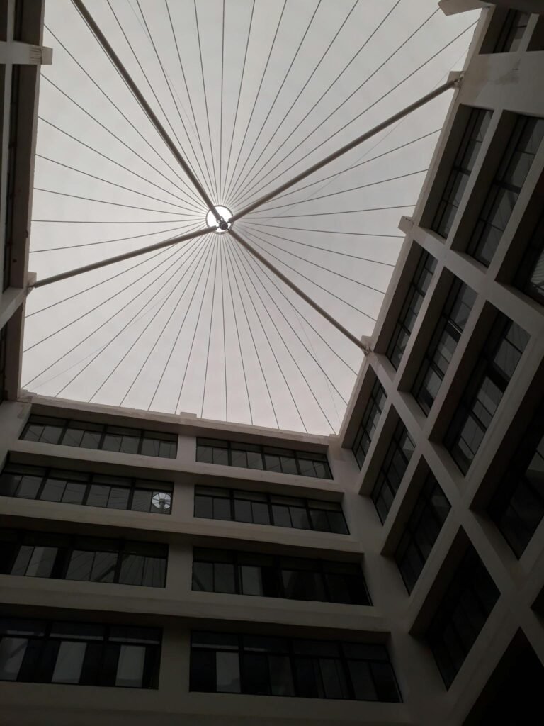 Upward view of a modern atrium with a geometric glass roof design.